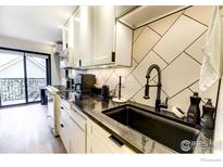 Modern kitchen features sleek black countertops, a black sink, and stylish white cabinetry for a contemporary look at 1800 Pearl St # 15, Boulder, CO 80302