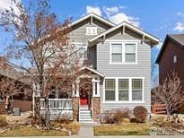 Charming two-story home with gray siding, stone accents, a red front door, and a welcoming front porch at 2014 Pintail Dr, Longmont, CO 80504