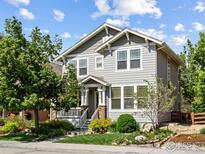 Charming two-story home with a covered front porch, manicured lawn, and lush landscaping at 2014 Pintail Dr, Longmont, CO 80504