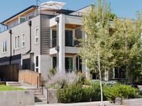 Modern exterior showcasing a rooftop patio, white and grey siding, and beautifully landscaped front yard with flowers and greenery at 2125 Eliot St, Denver, CO 80211