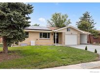 Charming brick ranch-style home with solar panels, a well-maintained lawn, and an attached garage at 5329 Flower Cir, Arvada, CO 80002