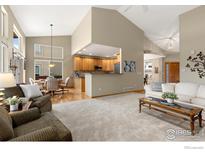 Open-concept living room featuring vaulted ceiling, neutral color palette, and pass-through to the kitchen at 735 Orchard Ct, Louisville, CO 80027