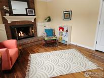 Cozy living room featuring a brick fireplace, hardwood floors, and a playful area at 7624 S Race St, Centennial, CO 80122