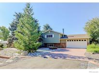 Charming exterior view of home featuring brick driveway, stone accents, and lush landscaping at 9852 Zephyr Dr, Broomfield, CO 80021