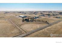 Expansive aerial view of a rural property featuring a home, a large metal building, and open fields at 1050 S Manila Rd, Bennett, CO 80102