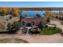 Stunning waterfront home with lush landscaping and mature trees surrounding the property at 10752 County Road 7, Longmont, CO 80504