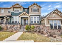 Inviting townhome featuring a beautiful stone facade, well-manicured lawn, and a welcoming front porch at 1856 Kalel Ln, Louisville, CO 80027