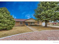 Charming single-story brick home with a well-manicured front yard and mature trees at 2407 Horseshoe Cir, Longmont, CO 80504
