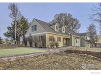 Charming single Gathering home with light green siding, red shutters, well-kept front yard, and mature trees at 620 Highway 52, Erie, CO 80516