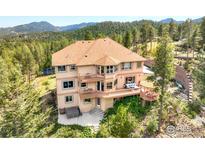 Beautiful three-story home with multiple balconies overlooking a treed lot, hot tub, and mountains at 12023 Coal Creek Heights Dr, Golden, CO 80403
