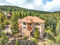 Stunning multi-story home with a wooden deck, beautiful trees, and a mountain view at 12023 Coal Creek Heights Dr, Golden, CO 80403