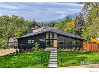 Striking home featuring a modern design, lush green lawn, and mountain views, with minimalist hardscape at 1580 Moss Rock Pl, Boulder, CO 80304