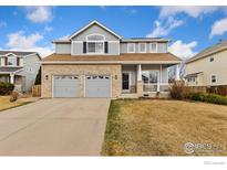 Charming two-story home featuring a brick facade, covered porch, and two-car garage at 16478 Marion St, Thornton, CO 80602