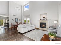 Bright living room featuring hardwood floors, fireplace, and adjacent dining area with modern decor at 16478 Marion St, Thornton, CO 80602