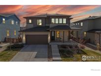 Inviting two-story home featuring stone accents, covered front porch, manicured lawn, and attached two-car garage at 420 Pleades Pl, Erie, CO 80516