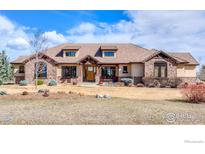 Single-story home featuring a tile roof, stone accents, inviting front entry, and landscaped front yard at 8604 Portico Ln, Longmont, CO 80503