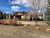 Beautiful stone and stucco home with a well-maintained lawn and mature trees at 8604 Portico Ln, Longmont, CO 80503