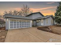 Charming home with a garage, gray siding, a manicured lawn and a beautiful sunset sky at 911 Timber Ct, Longmont, CO 80504