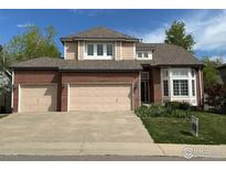 Two story home featuring an attached three car garage, brick, and manicured landscaping at 1069 Monarch Way, Superior, CO 80027