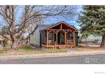 Charming home featuring a wooden porch, muted green siding, and well-maintained landscaping at 329 2Nd St, Frederick, CO 80530