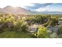 Breathtaking aerial view of a neighborhood home nestled amid lush greenery with the mountains as a stunning backdrop at 3380 Longwood Ave, Boulder, CO 80305