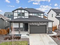 Beautiful two-story home with a stone facade and covered front porch and 2-car garage at 4764 Kipp Pl, Brighton, CO 80601