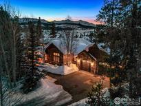 Stunning exterior of a mountain home with snow-covered roof, lit driveway, and mountain views in the background at 500 Highfield Trl, Breckenridge, CO 80424