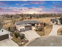 Stunning aerial view of home with modern garage, solar panels, and beautifully landscaped backyard and long driveway at 8568 Foxhaven Ct, Niwot, CO 80503