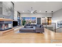 Open living room featuring a fireplace, hardwood floors, a large window, and a gray sectional sofa at 8568 Foxhaven Ct, Niwot, CO 80503