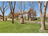 Charming gray home with beautiful landscaping and mature trees lining the driveway at 9610 Avocet Ln, Lafayette, CO 80026