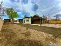 Wide angle of single story home showing a dirt yard, wood and white exterior and blue sky overhead at 11488 County Road 20, Fort Lupton, CO 80621