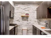 The kitchen features dark cabinets, stainless steel appliances, and a unique backsplash at 1401 W 85Th Ave # B-405, Denver, CO 80260