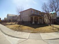 Two-story home featuring stone accents, a covered porch, and a well-maintained lawn on a sunny day at 14992 E 116Th Pl, Commerce City, CO 80603