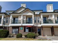 Townhome featuring brick and siding, covered patio, upper-level balcony, garage, and manicured front yard at 1881 Mallard Dr, Superior, CO 80027