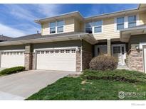 Charming townhome featuring a two-car garage, well-maintained lawn, and stone accents at 3000 E 112Th Ave, Northglenn, CO 80233