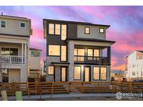 Modern three-story home featuring stone accents and a charming second-story balcony at 928 Farrier Ln, Lafayette, CO 80026