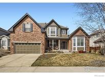 Charming two-story brick home with a well-maintained lawn and inviting front porch at 1526 Chukar Dr, Longmont, CO 80504