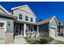 Charming two-story home featuring a cozy front porch, American flag, and meticulous landscaping at 2407 Tyrrhenian Cir, Longmont, CO 80504