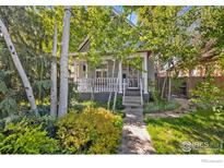 Charming home featuring a quaint front porch, mature trees, and lush landscaping at 3056 W 34Th Ave, Denver, CO 80211