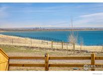 Scenic lake view featuring clear blue water and a distant cityscape under a bright sky at 16568 W 92Nd Pl, Arvada, CO 80007