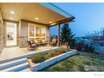 An inviting covered patio with outdoor seating and a view of the landscaped backyard, perfect for relaxing and entertaining at 1806 Blue Star Ln, Louisville, CO 80027