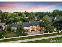Stunning aerial view of a sprawling home surrounded by lush landscaping and a manicured lawn, at sunset at 7155 Rustic Trl, Boulder, CO 80301