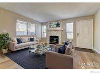 Bright living room with a stone fireplace, wood floors, and lots of natural light at 9501 W 89Th Cir, Broomfield, CO 80021