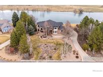 Stunning waterfront estate featuring a circular driveway, mature trees, and a beautifully landscaped front yard at 10391 E Goose Haven Dr, Lafayette, CO 80026