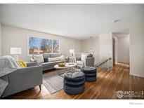 Comfortable living room with hardwood floors, large windows, and neutral decor at 1529 Ashcroft Dr, Longmont, CO 80501
