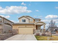Inviting two-story home with a two-car garage, stone accents, and a charming covered front porch at 17995 E 107Th Pl, Commerce City, CO 80022