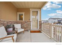 Inviting covered front porch with comfortable seating area, stone accents and welcome mat at 17995 E 107Th Pl, Commerce City, CO 80022