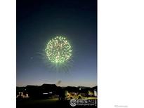 A vibrant fireworks display illuminates the night sky over the silhouette of neighborhood homes below at 2117 Cadman St, Berthoud, CO 80513