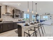 Modern kitchen features a breakfast bar, stylish countertops, stainless steel appliances, and herringbone backsplash at 2746 Bear Springs Cir, Longmont, CO 80503