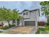 Charming two-story home featuring a well-manicured lawn, gray siding, and a welcoming front entrance at 230 Bonanza Dr, Erie, CO 80516